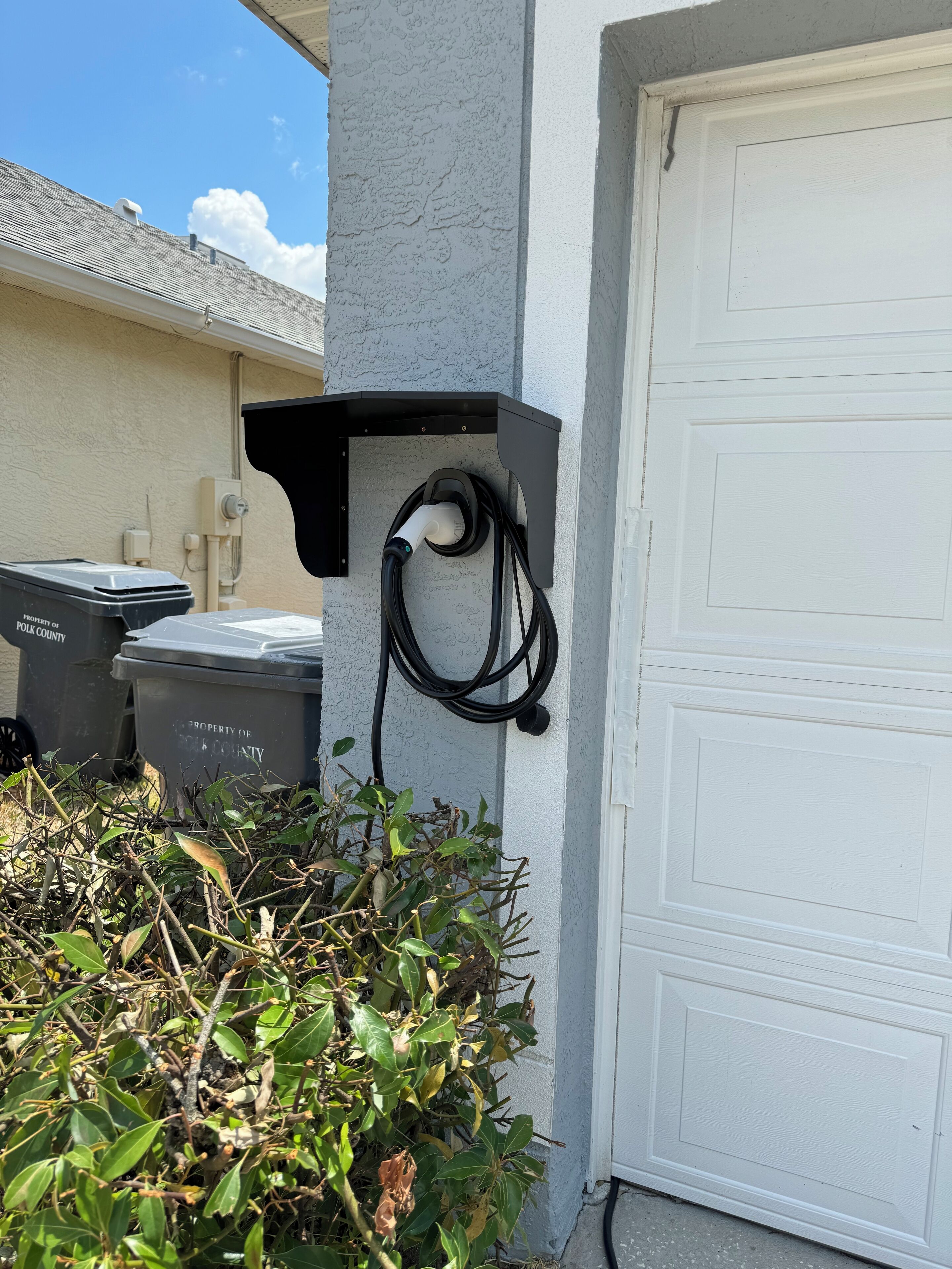 A utility box attached to a building's exterior wall, with a cable connected to it.
