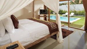 Een slaapkamer met een bed, een televisie en uitzicht op een zwembad.