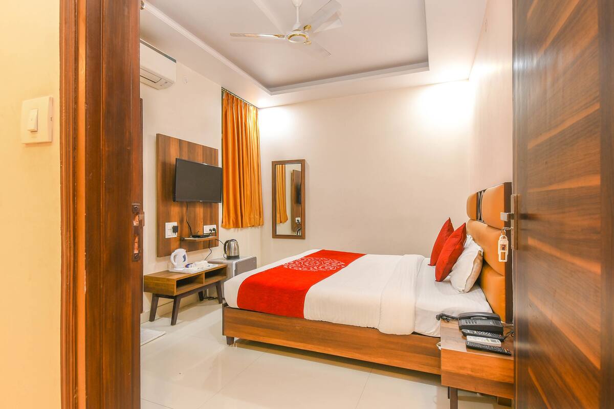 A hotel room with a wooden bed, a desk with a telephone, a television, and a mirror.