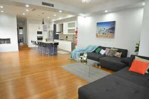 Una sala de estar moderna con un sofá gris, una mesa de centro y un comedor con una cocina al fondo.