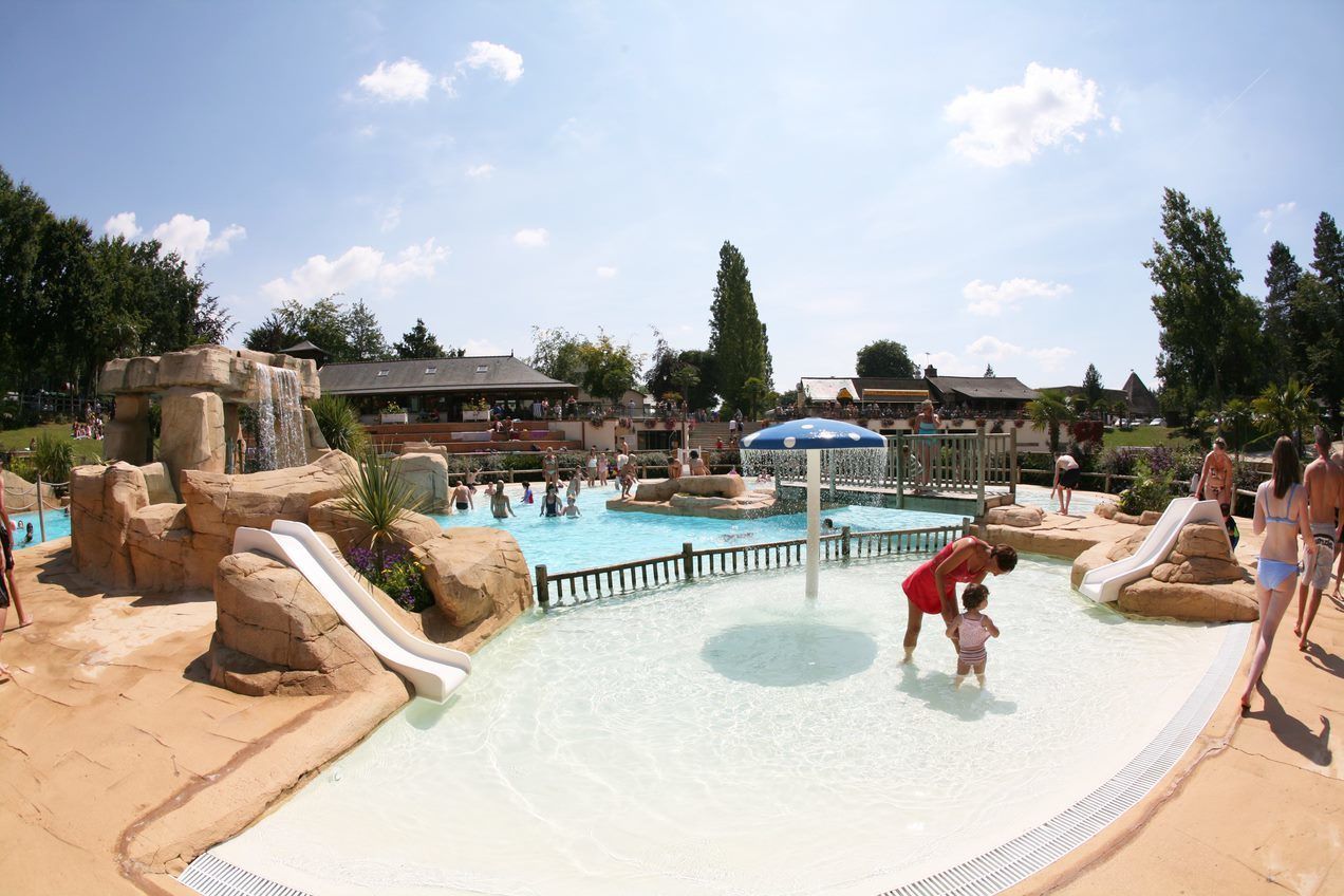 Parque acuático con piscina, toboganes y terreno rocoso.