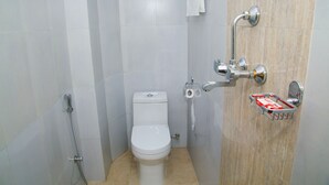 Un baño pequeño y moderno con inodoro, ducha y barra para toallas.