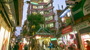 Un edificio de varios pisos con diversas tiendas en la planta baja, incluyendo una lavandería y una joyería.
