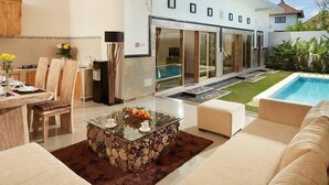 A modern living room with a glass coffee table, a sofa, and a dining area with chairs. - 3Bedrooms Central Seminyak walking distance to the Boutique shop,Restaurant,Bar (Seminyak)