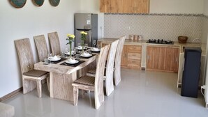 A dining area with a wooden table and chairs, a kitchen with wooden cabinets, and a refrigerator. - 3Bedrooms Central Seminyak walking distance to the Boutique shop,Restaurant,Bar (Seminyak)
