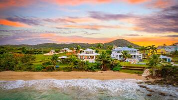 A beachfront property with multiple houses, a swimming pool, and a view of the ocean.