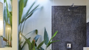 A bathroom with a mosaic wall, a shower area, and a plant wall.