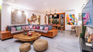 A modern living room with a sectional sofa, wooden coffee table, and woven poufs.