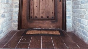 A wooden door with a metal handle and a peephole, set in a brick wall with a tiled entrance. - BEAUTIFUL VERY SPACIOUS home in heart of Branson - Hot Tub, Game Room,Large Yard (Branson)