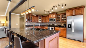 A modern kitchen with granite countertops, stainless steel appliances, and wooden cabinets. - BEAUTIFUL VERY SPACIOUS home in heart of Branson - Hot Tub, Game Room,Large Yard (Branson)