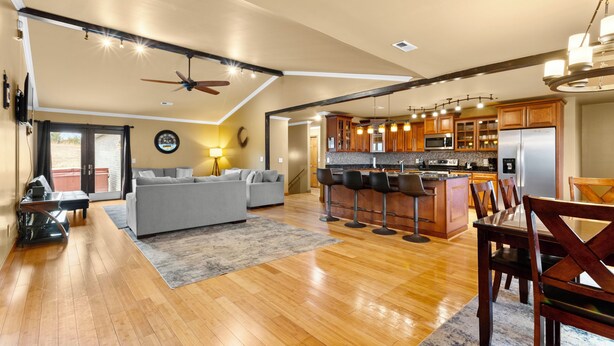 A spacious living area with a sofa, a dining table with chairs, a kitchen with wooden cabinets and modern appliances, and a ceiling fan. - BEAUTIFUL VERY SPACIOUS home in heart of Branson - Hot Tub, Game Room,Large Yard (Branson)