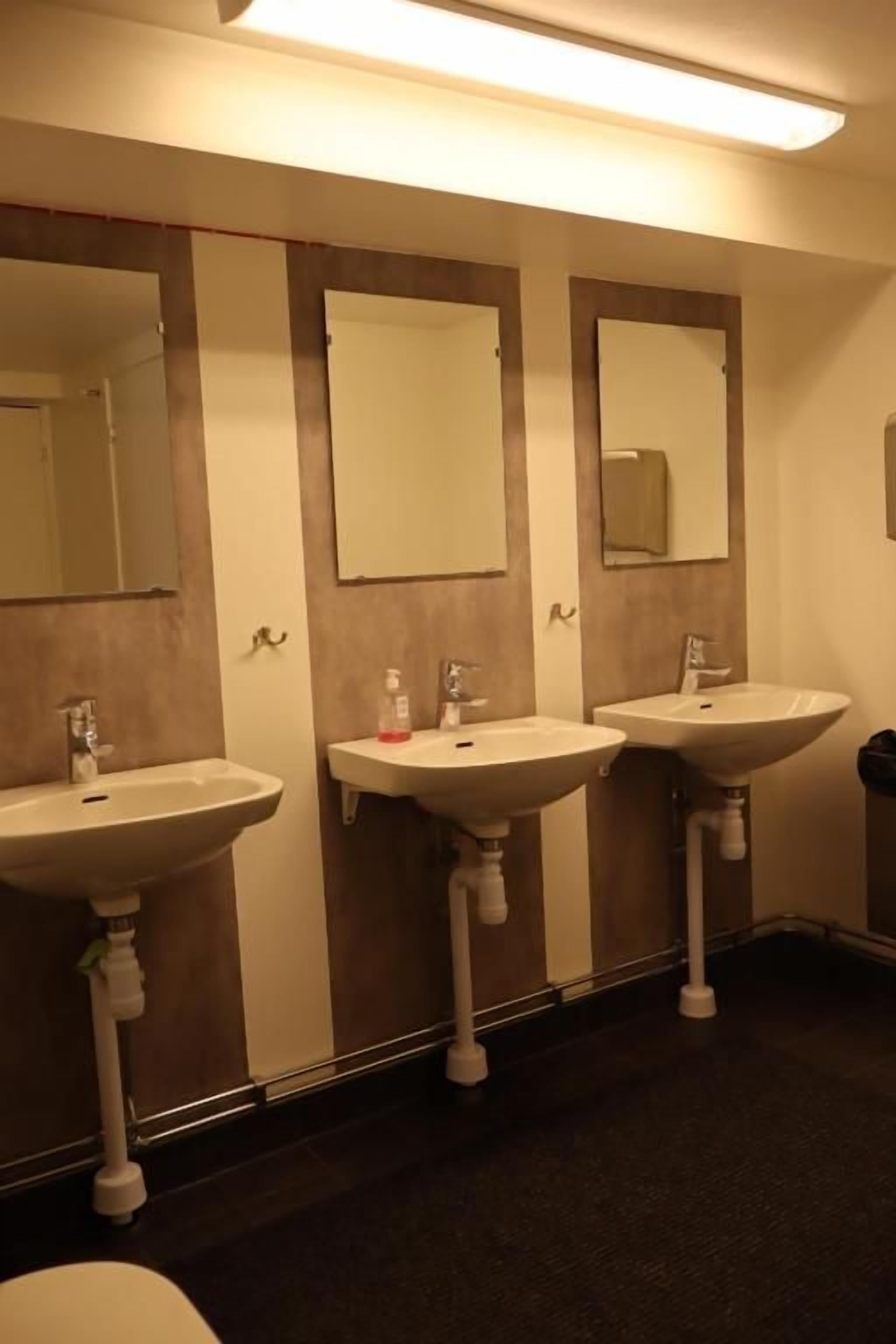 Sanitário com três pias e espelhos.