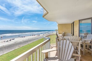 Un balcone con vista sulla spiaggia e sull'oceano. Sono presenti diverse poltrone in stile Adirondack e un tavolo con sedie.