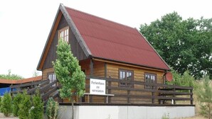 Een houten gebouw met een rood dak, een bord met de tekst 'Ferienhaus zu vermieten' en een houten hek.