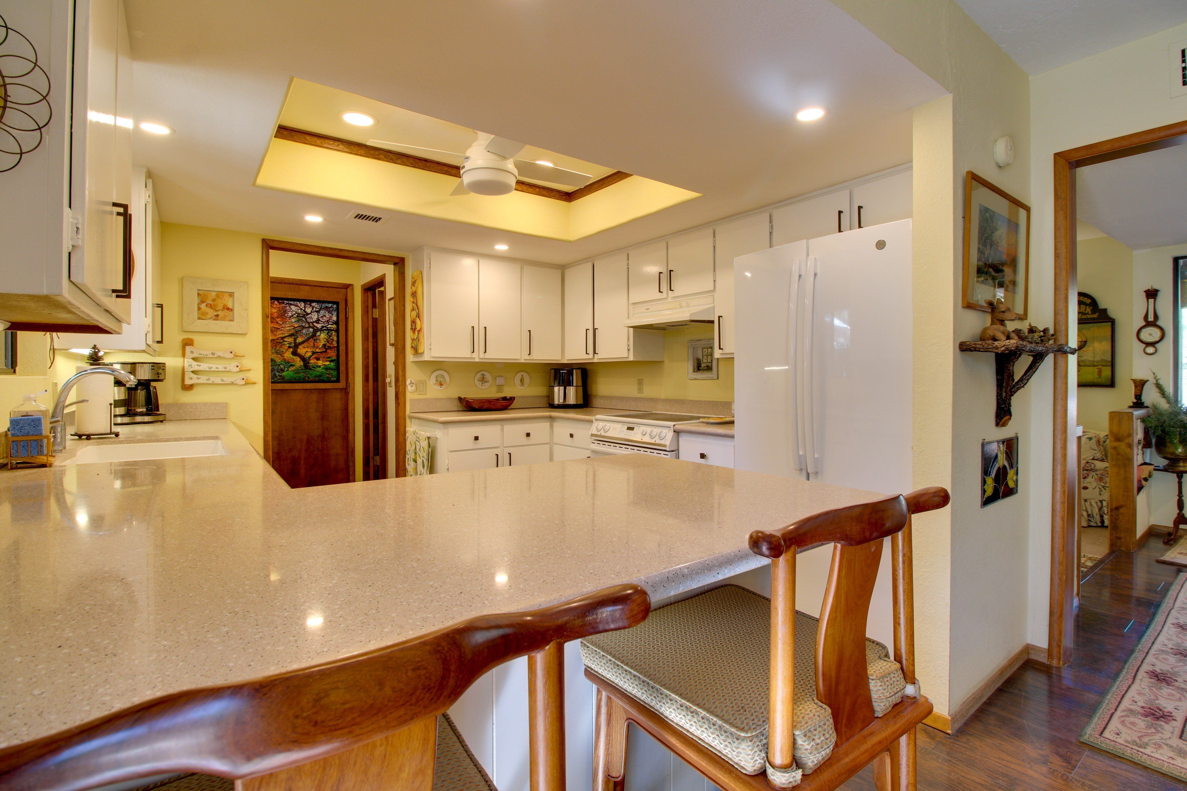 A kitchen with a large island, white cabinets, and a ceiling fan.