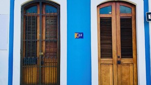 A building with two wooden doors and windows, each with a white frame and blue wall. - Quaint Colonial Home in Old San Juan (San Juan)