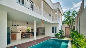 Et moderne hus med to etager, swimmingpool, balkon og en velplejet have.