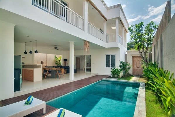 A modern two-story house with a swimming pool, a balcony, and a well-maintained garden.
