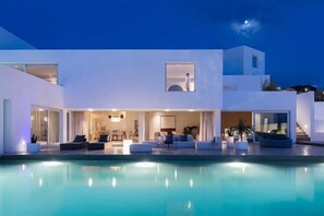 A modern, multi-story house with a swimming pool in the foreground.