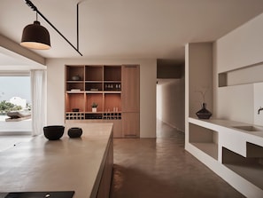 A modern kitchen with a wooden island, built-in shelves, and a minimalist design. - Andronis Arcadia Hotel (Santorini)
