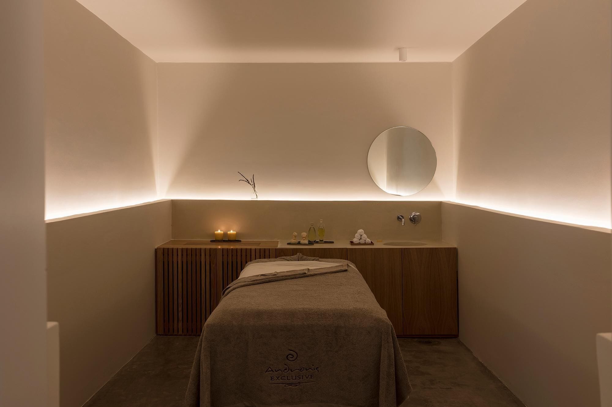 A modern bathroom with a wooden vanity, a round mirror, and a towel draped over a bench.