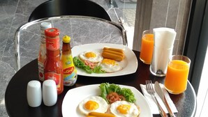 A breakfast table with plates of eggs, toast, and juice, salt and pepper shakers, and condiments. - Suthep Home & Hostel (Bangkok)