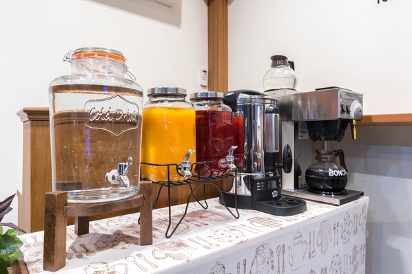 Una estación de bebidas con frascos grandes de vidrio y una máquina de café.