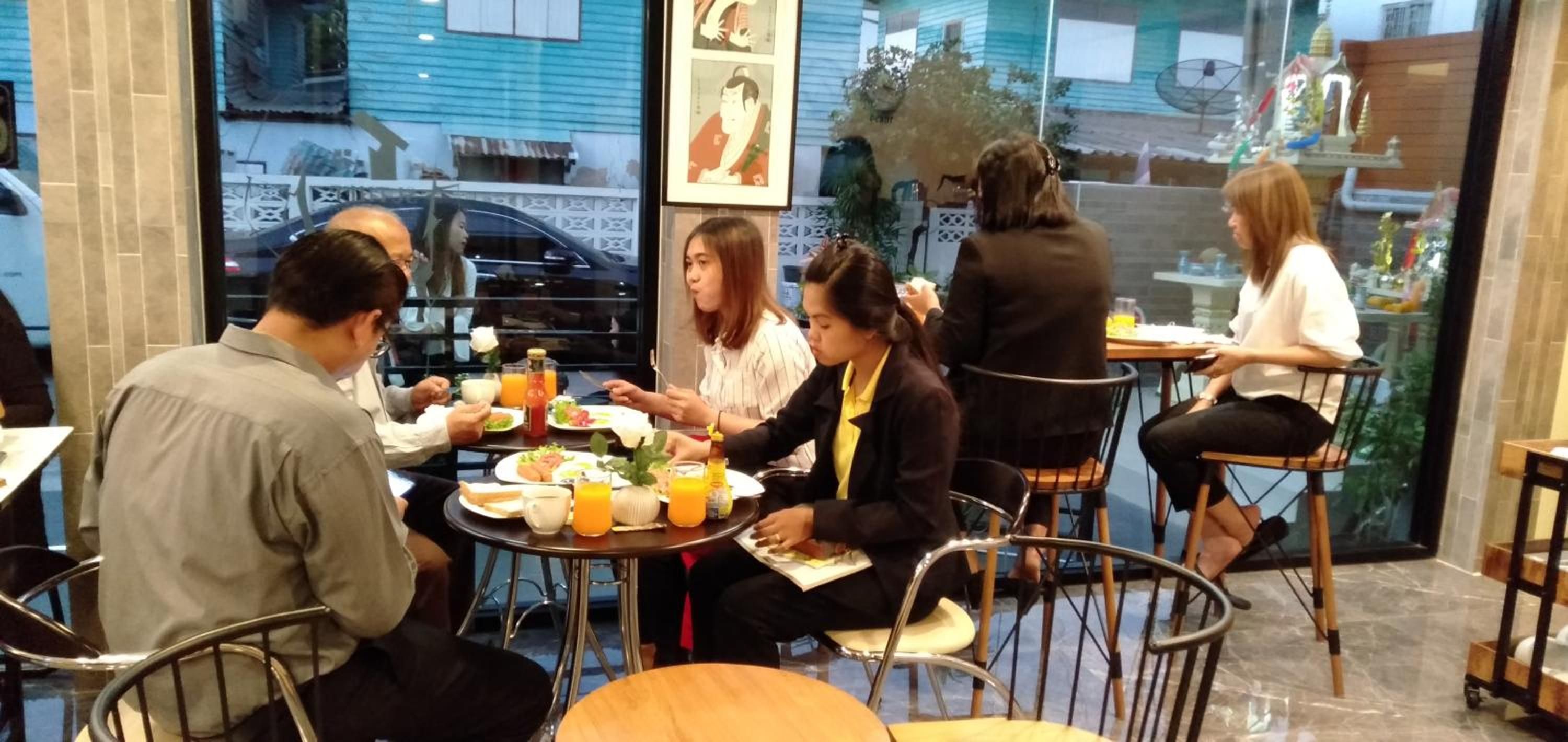 A group of people dining at a restaurant with a view of the street outside.