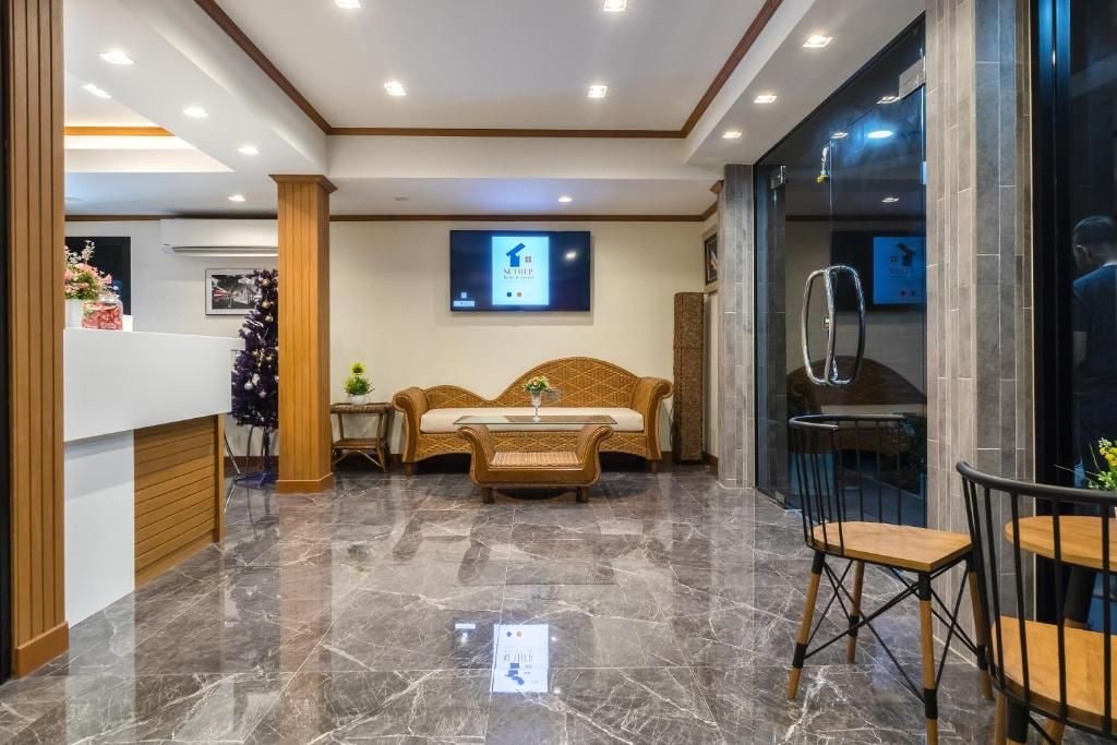 A lobby with a reception desk, a sofa, a coffee table, and a dining area with chairs.
