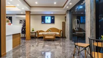 A lobby with a reception desk, a sofa, a coffee table, and a dining area with chairs.