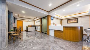 A modern hotel lobby with a reception desk, seating area, and a large mirror. - Suthep Home & Hostel (Bangkok)