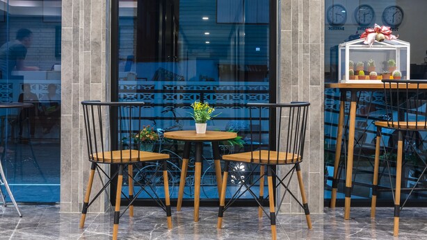 A modern interior with a glass door entrance, a small round table with two chairs, and a potted plant. - Suthep Home & Hostel (Bangkok)