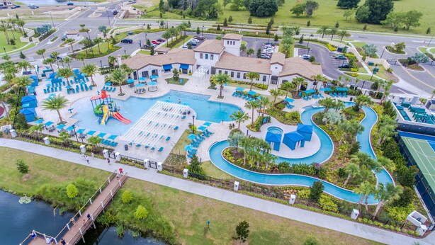 A resort with a large pool, a water slide, and a tennis court.