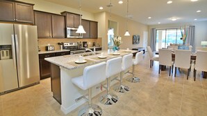 A modern kitchen with a central island, stainless steel appliances, and pendant lighting.