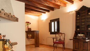 A rustic room with a wooden chair, a cabinet with drawers, a radiator, and a wooden shelf with decorative items. - Hotel Rural Princesa Kristina (Covarrubias)