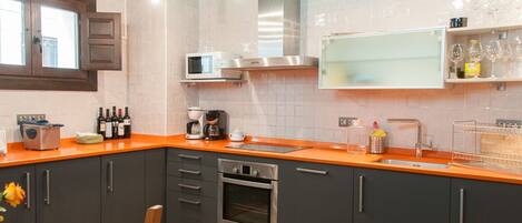 A modern kitchen with grey cabinets, an orange countertop, a built-in microwave, and a stainless steel oven.