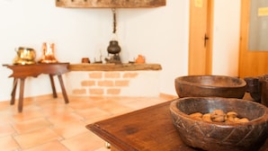 A rustic kitchen with a brick wall, wooden shelves, and a wooden table with bowls. - Hotel Rural Princesa Kristina (Covarrubias)