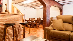 A cozy living area with a brick wall, wooden stools, a sofa, and a dining table with chairs. - Hotel Rural Princesa Kristina (Covarrubias)