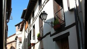 A narrow cobblestone street lined with white buildings featuring wooden doors and black railings. - Hotel Rural Princesa Kristina (Covarrubias)