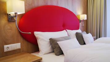 A hotel room with a large red headboard, white bedding, and two bedside lamps.