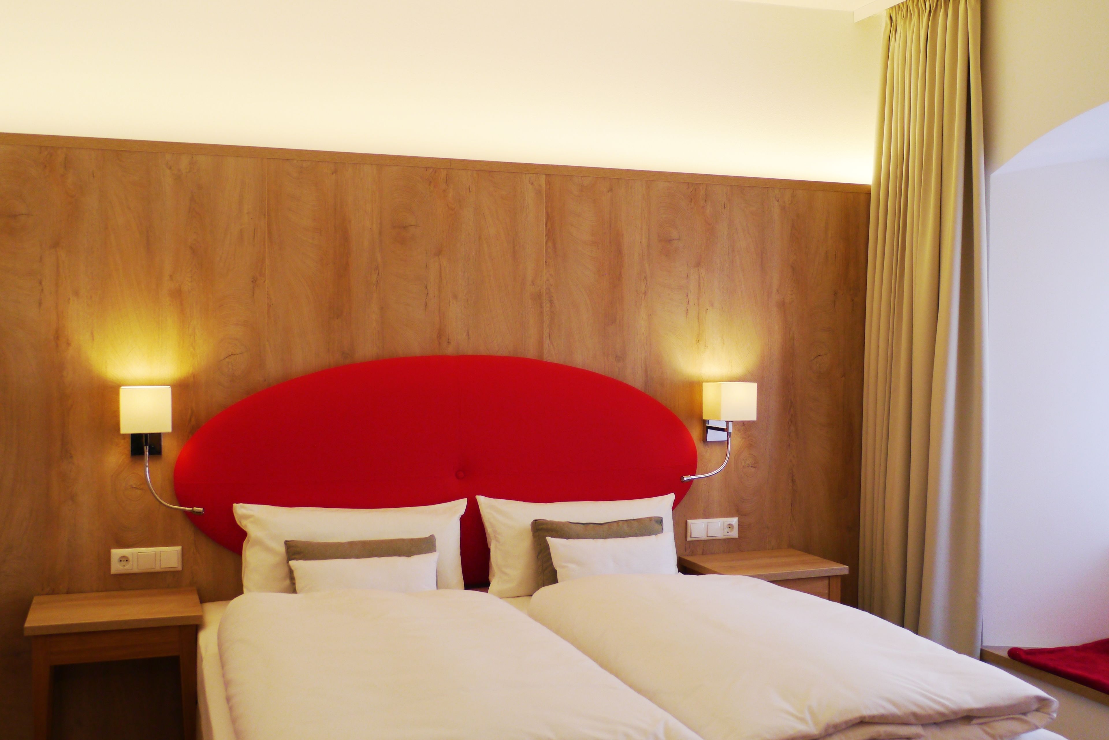 Una habitación de hotel con cabecera de madera, dos mesitas de noche y una cama con ropa blanca.