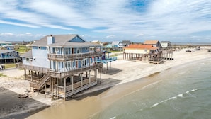 A beachfront property with multiple buildings, including a large house with a balcony and a smaller structure with a red roof. - Atlantis - Oceanfront Seating at its Finest! (Freeport)