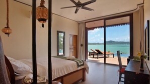 Un dormitorio con cama, ventilador de techo y vistas a un balcón con piscina y sillas de descanso.