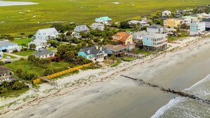 An aerial view of a coastal residential area with houses, a beach, and a damaged wooden structure near the shore. - East End Escape | Ocean Views, Spacious Deck & Quiet Beach Area Near Public Access (Folly Beach)