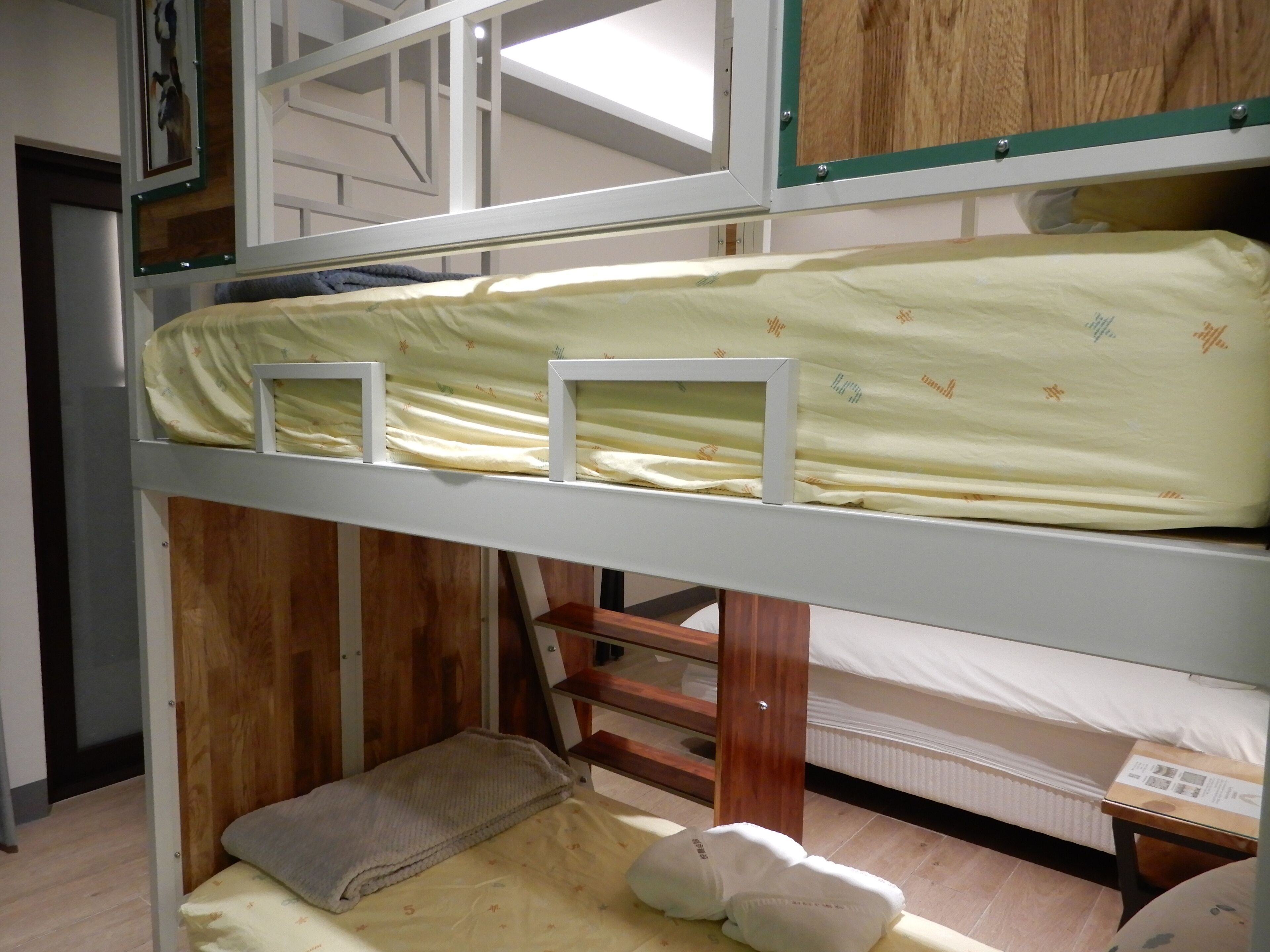Una cama litera con escalera de madera, una litera inferior con almohada y un colchón estampado con motivos florales.