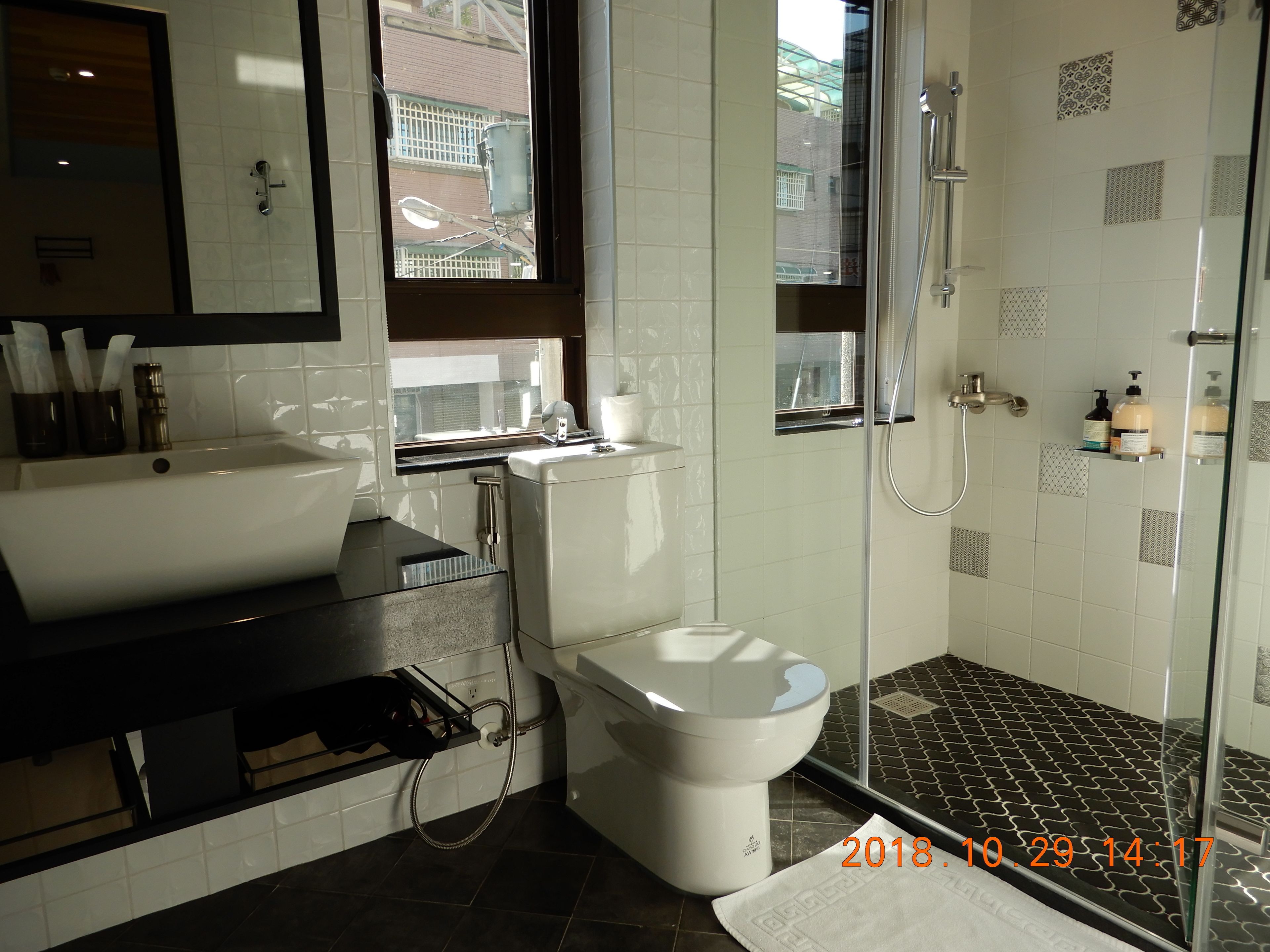 Une salle de bain moderne avec un grand lavabo blanc, des toilettes et une douche séparée par une paroi de verre.
