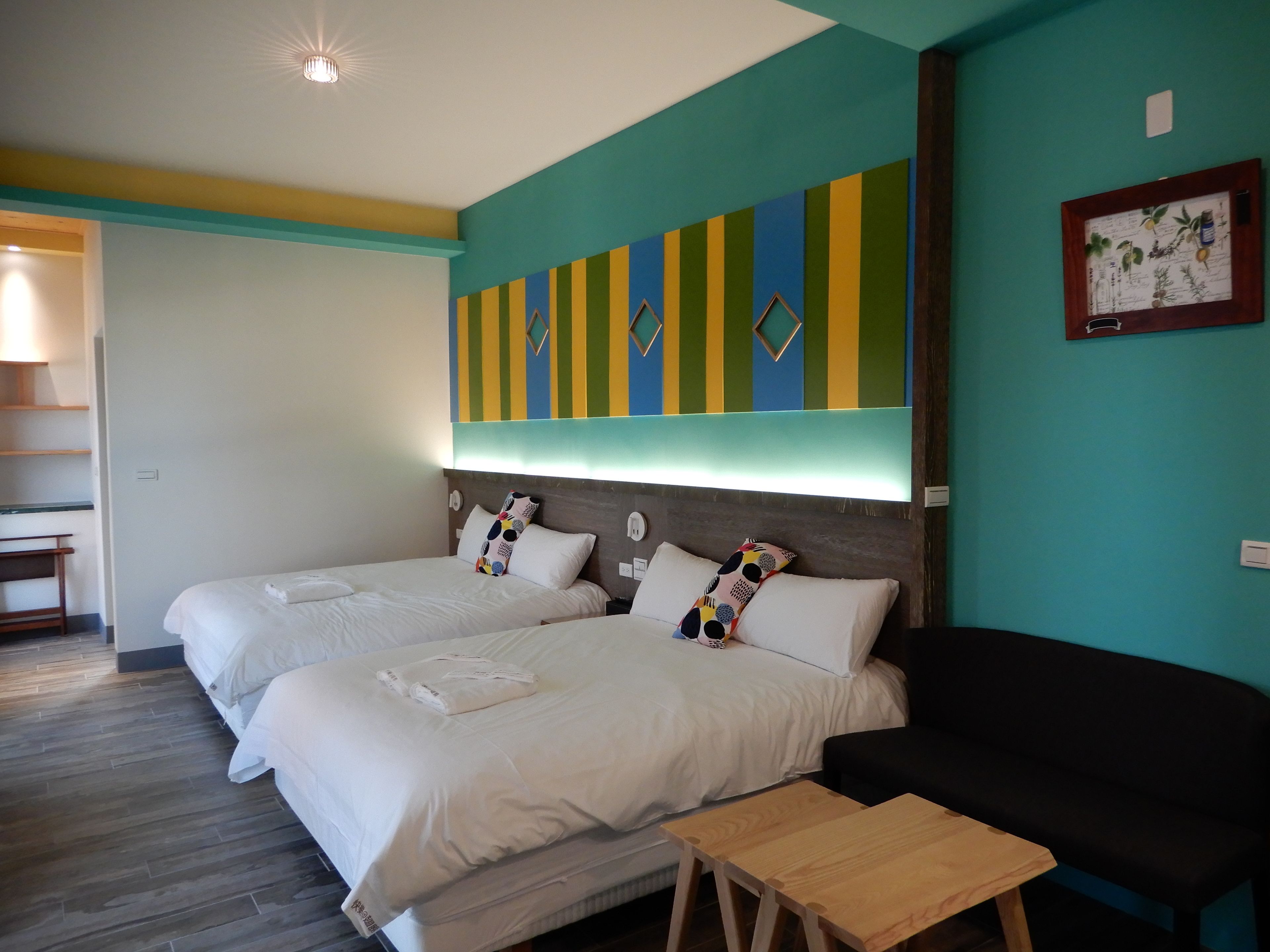 A hotel room with two beds, a wooden table, and a black chair.