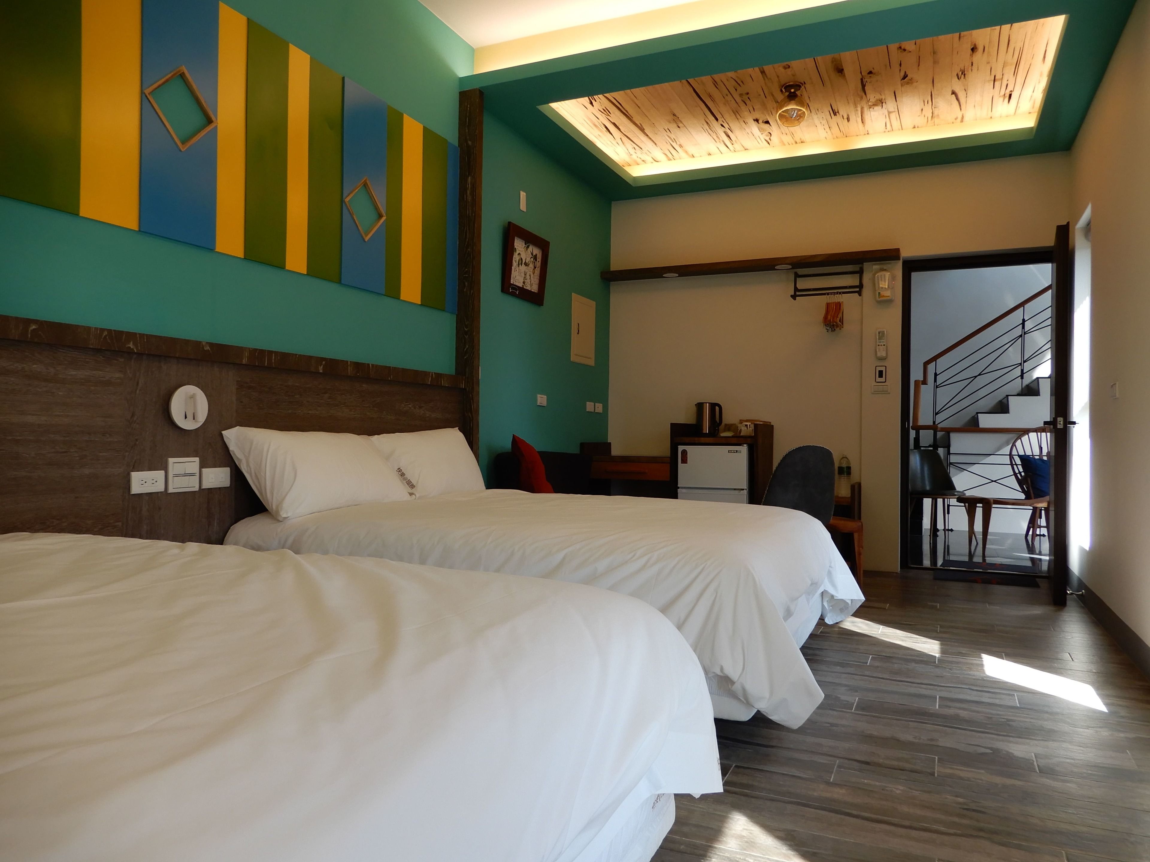 Een hotelkamer met twee bedden, een houten plafond en een trap naar een hoger gelegen niveau.