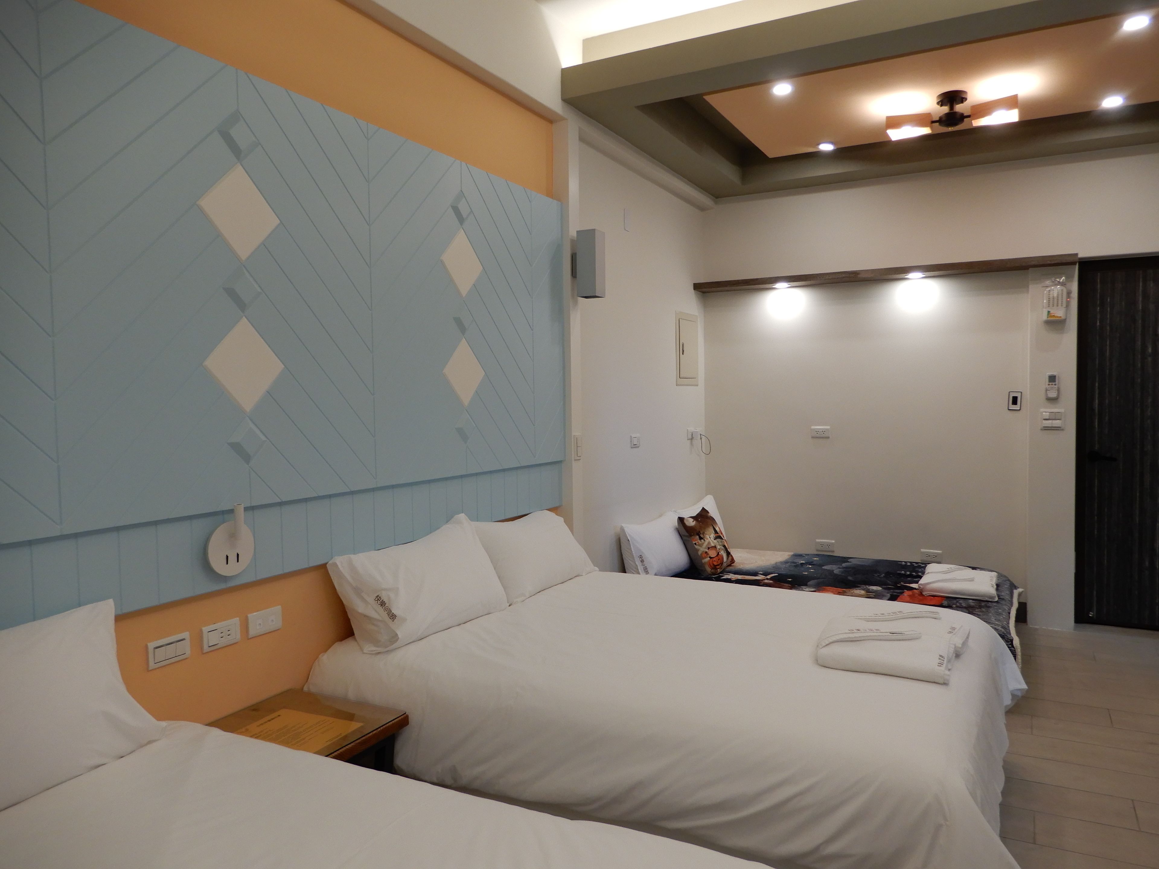 A hotel room with two beds, a large wall mural, and a ceiling fan.