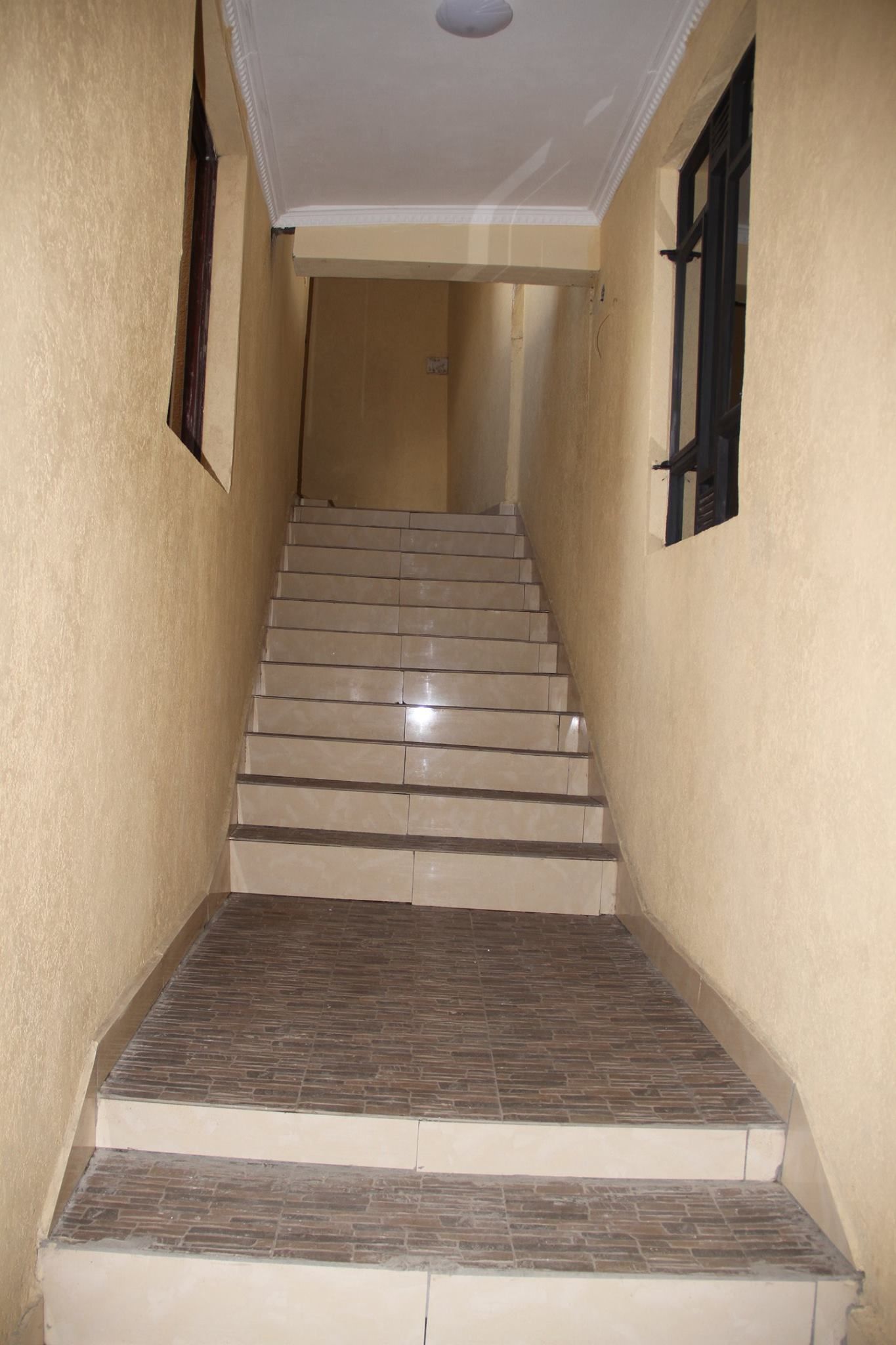 Una escalera con paredes color beige y techo blanco.
